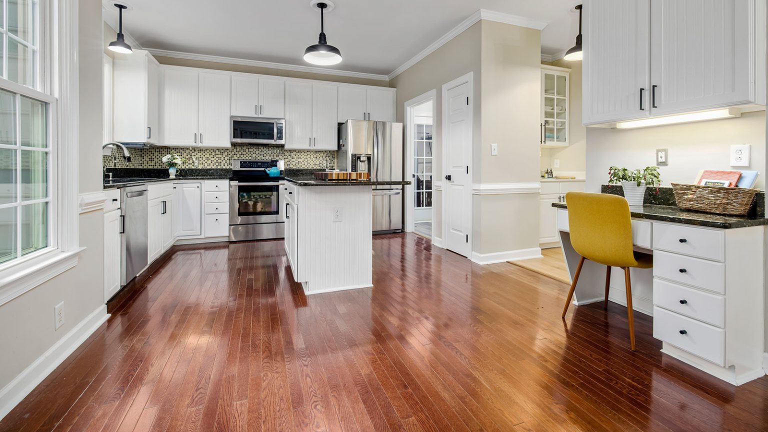 A renovated kitchen with glossy hardwood floors and fresh white cabinets